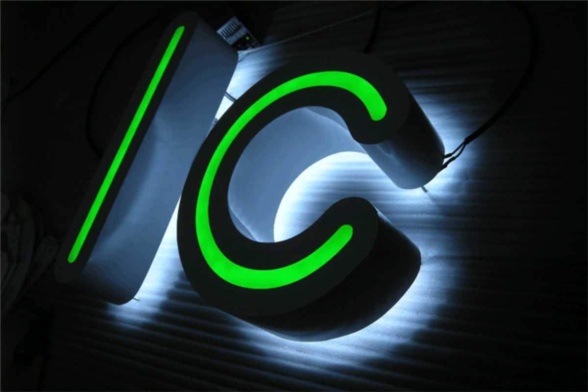Bright neon green channel letters "I" and "C" with backlighting against building