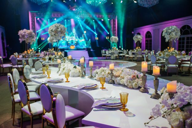Long dinner table decorated with white flowers, shiny candles and golden glasses stands in a beautiful hall Event Branding